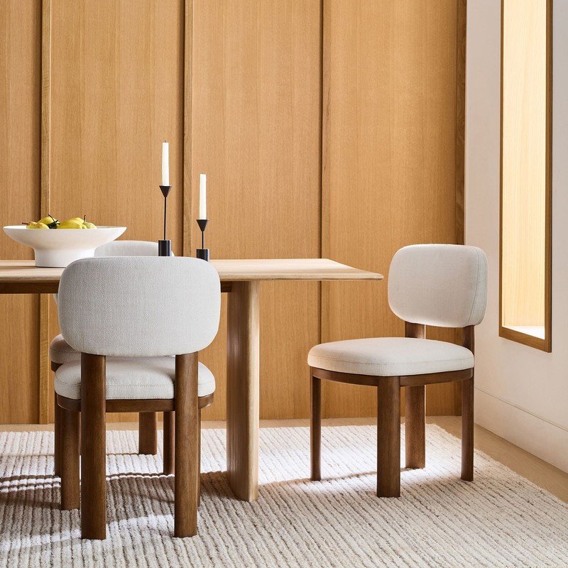Sillas de comedor tapizadas junto a una mesa de madera de la colección de Kalida